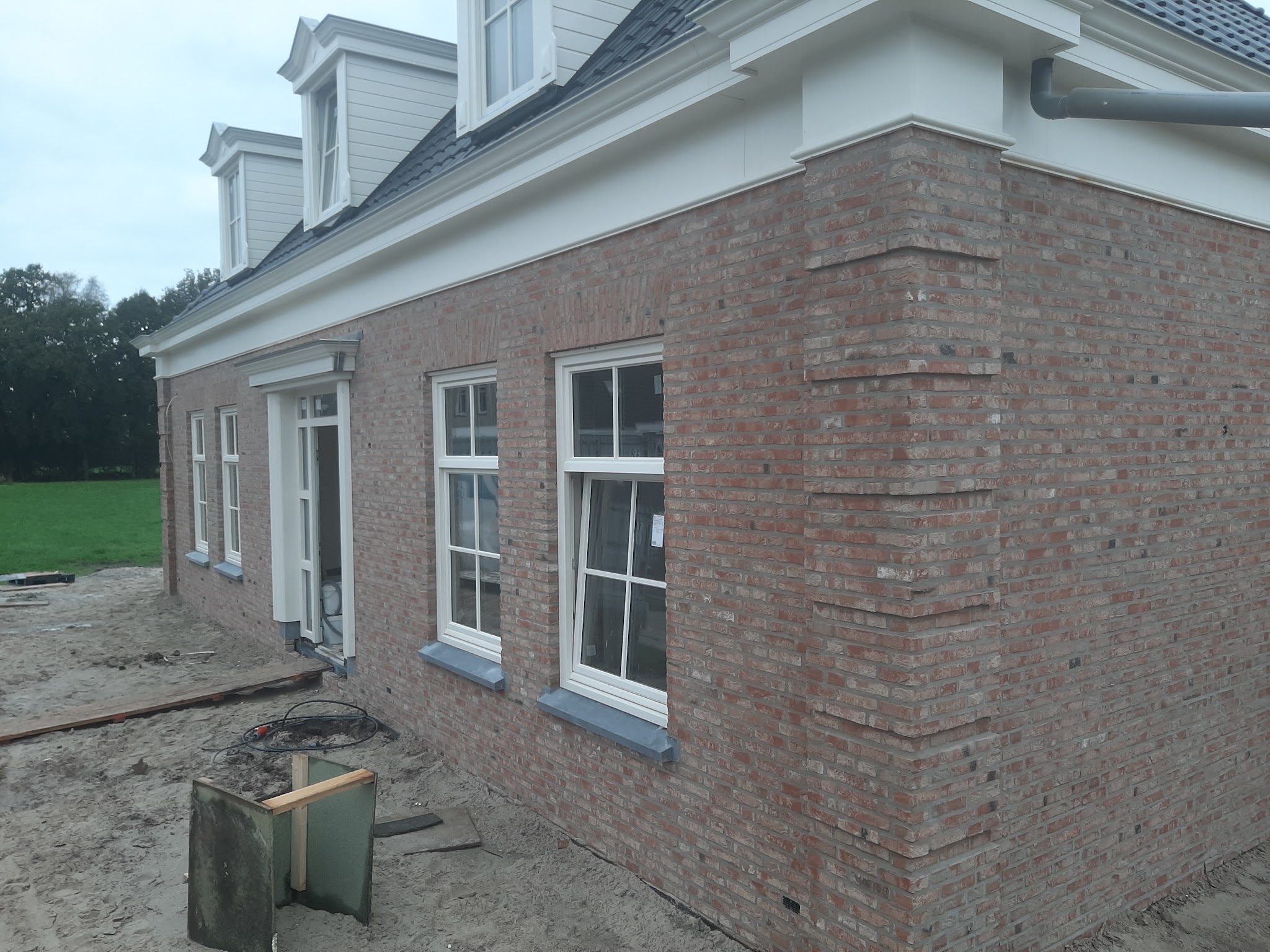 Nieuwe woning met roodbruin metselwerk, witte kozijnen en dakkapellen, net gevoegd