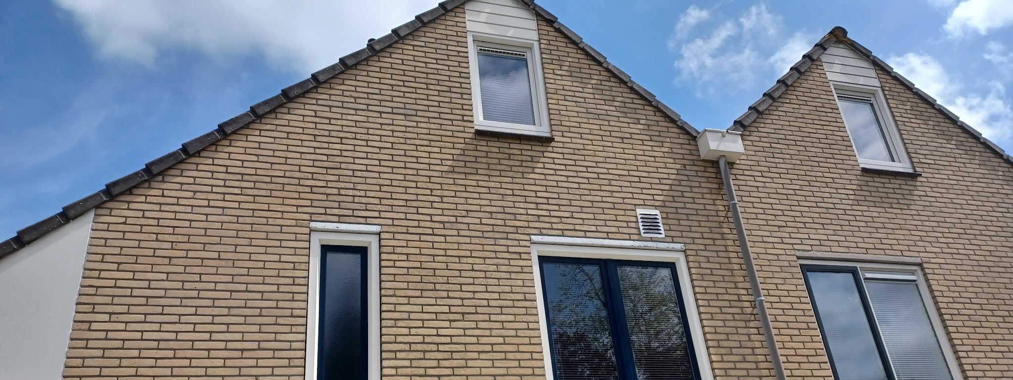 Twee puntgevels van gele baksteen met nieuwe voegen