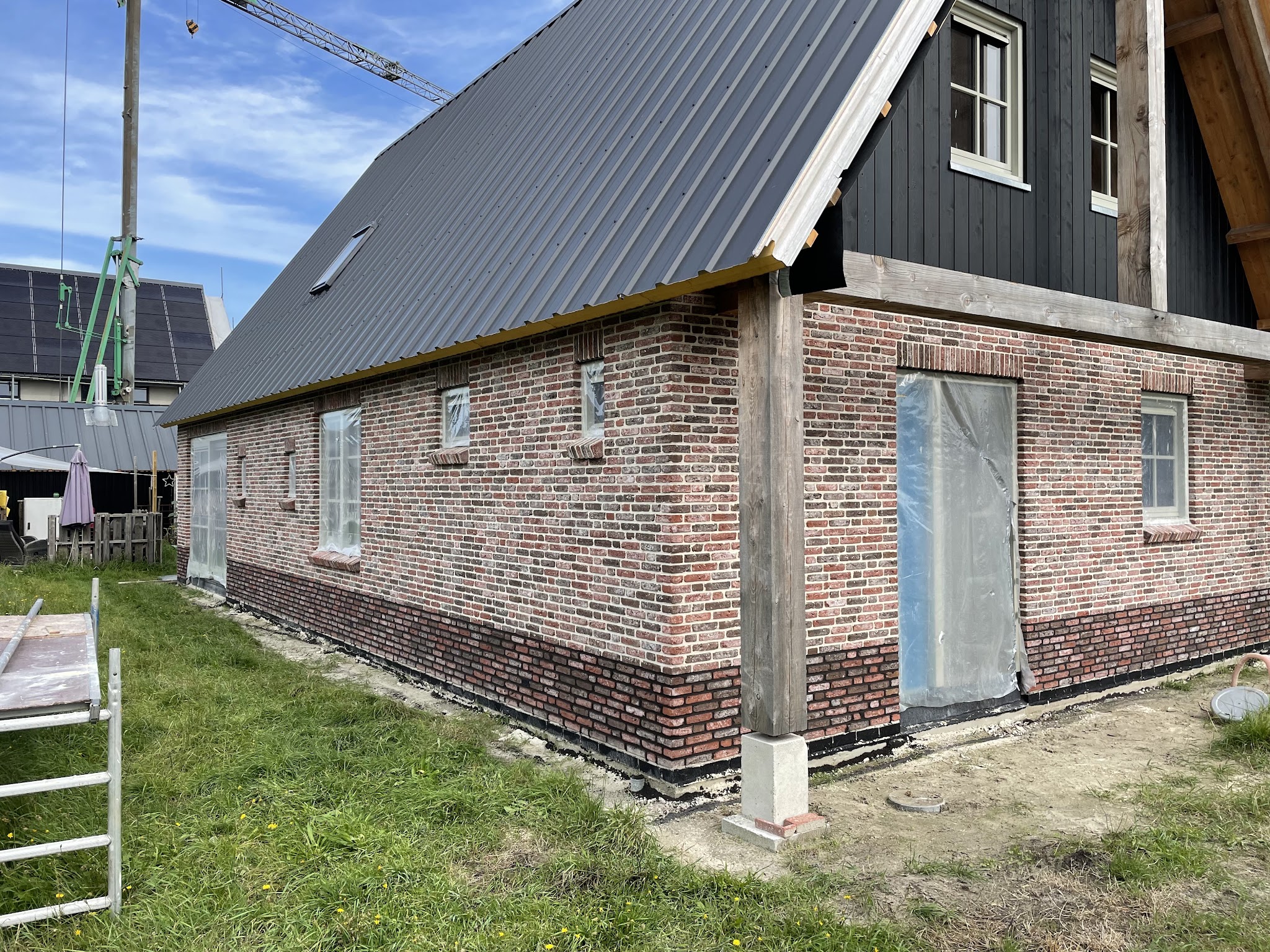 Woning met oud rood metselwerk en donkere houten gevel, voegwerk aan de onderbouw