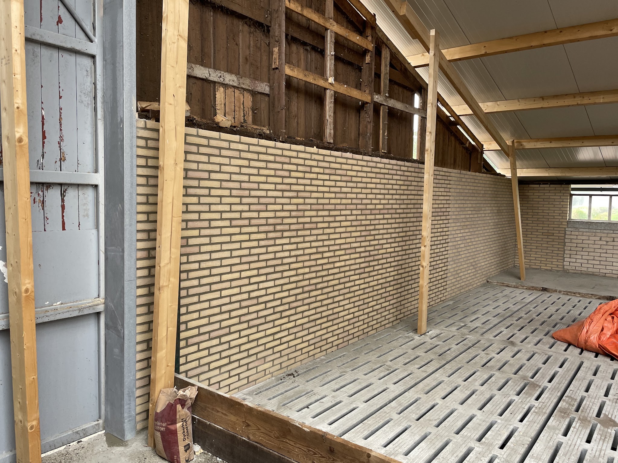 Binnenmuur van gele baksteen in een houten schuur, opnieuw gevoegd