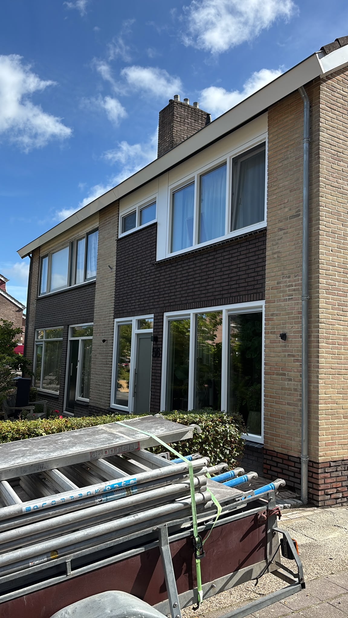 Twee-onder-een-kapwoning van gele en donkere baksteen met steigermateriaal ervoor